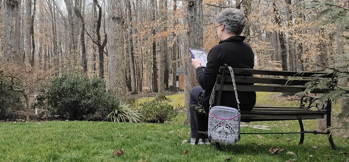 A woman sitting on a bench reading a book.