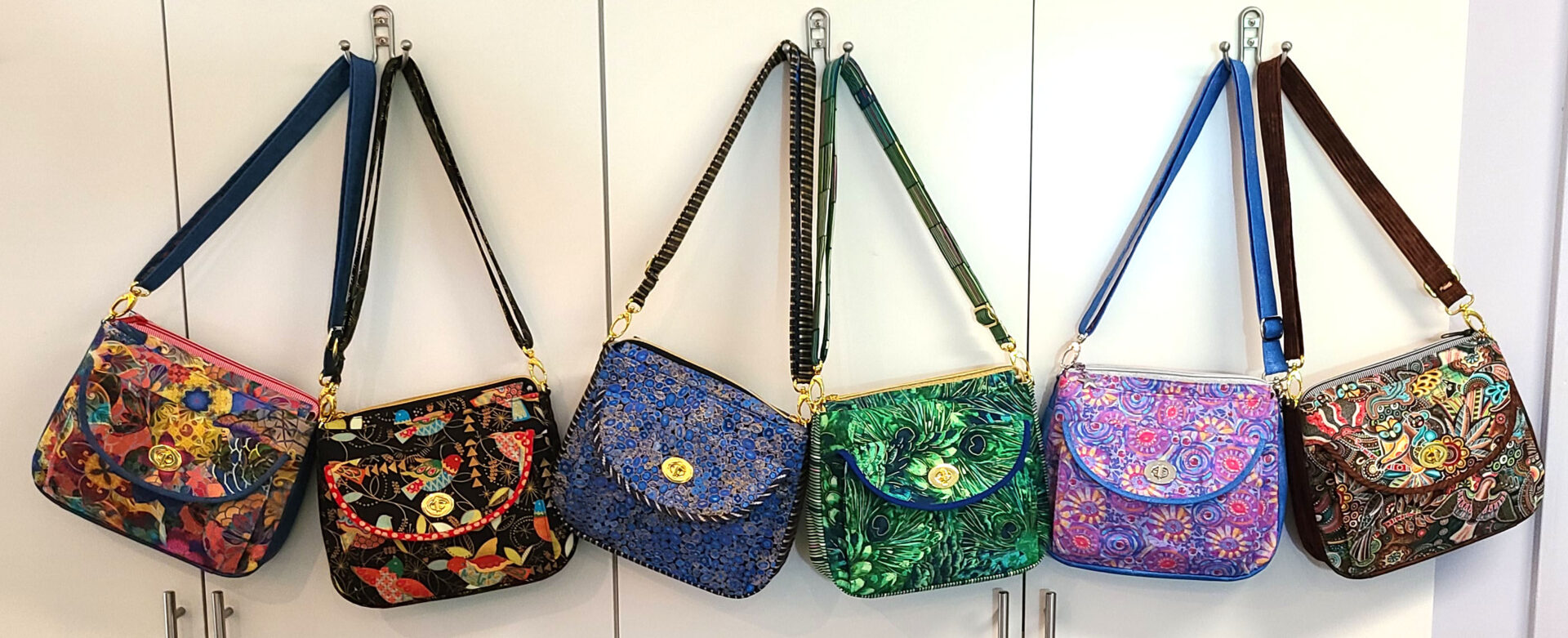 A group of colorful handbags hanging on a wall.