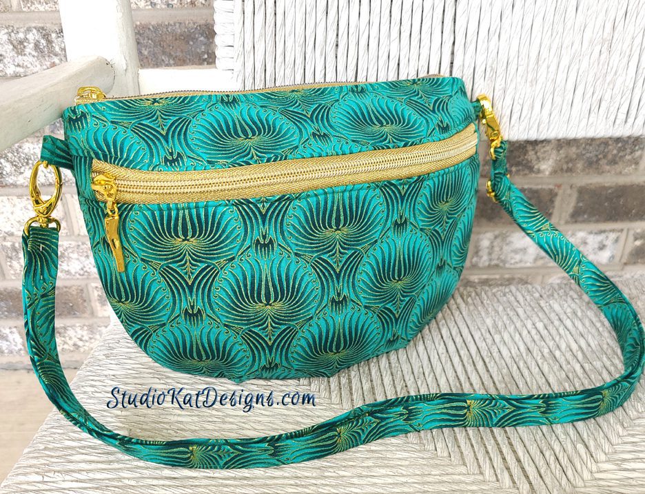A teal purse with a gold zipper on it.
