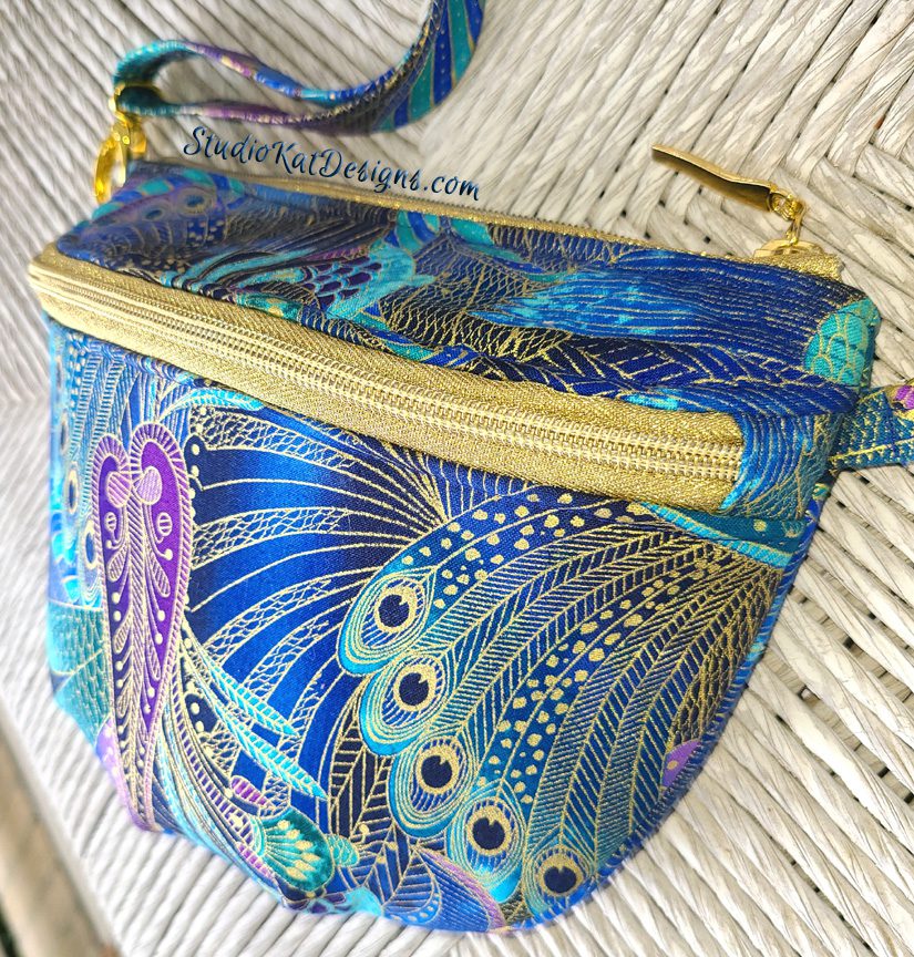 A blue and gold paisley fanny pack with a gold zipper.