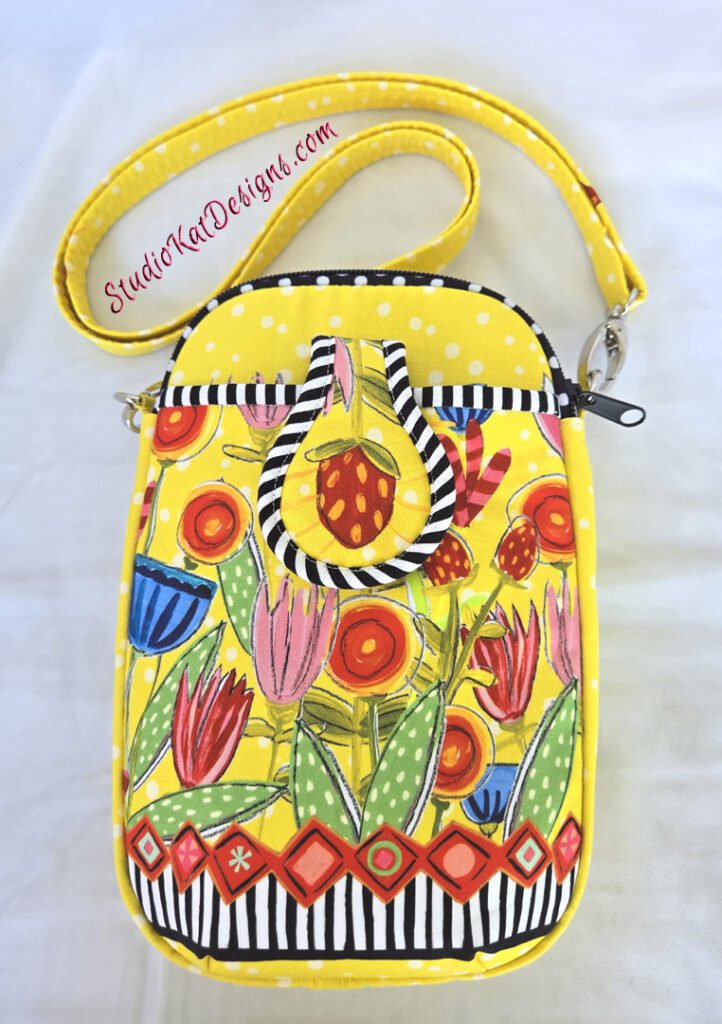 A yellow purse with flowers and stripes on it.