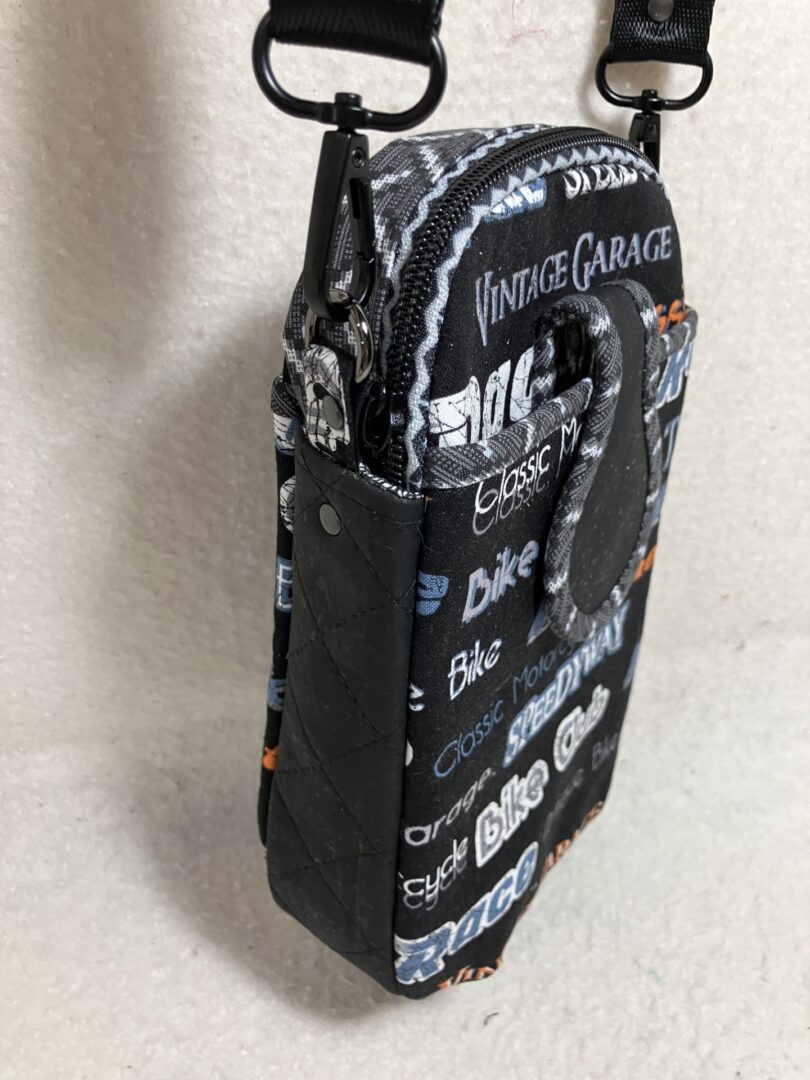 Black and white printed crossbody bag with logos and text.