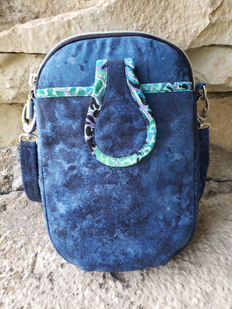 Small blue denim pouch with a patterned trim and clasp.