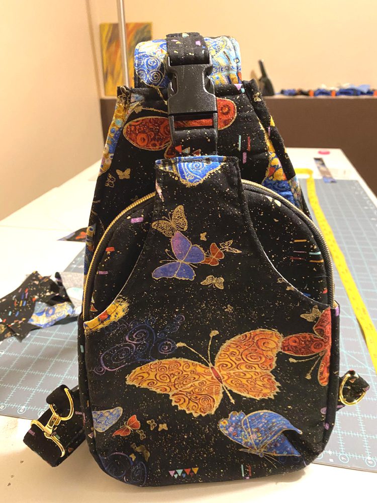 Backpack with colorful butterfly design on a dark background.