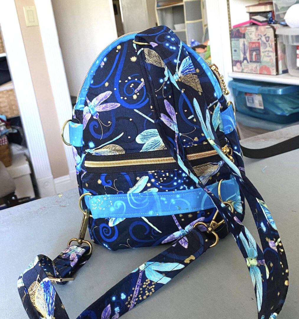 A colorful blue backpack with a celestial and floral pattern.
