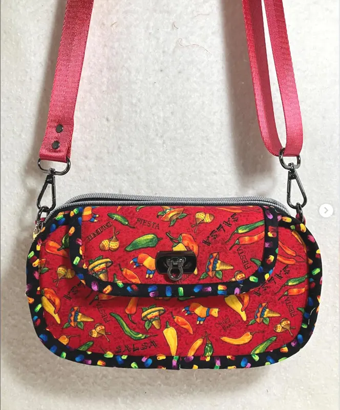Colorful handbag with chili pepper pattern and pink strap.