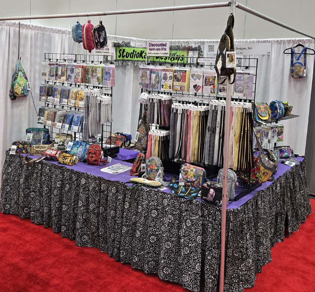 Craft booth with handmade scarves and accessories at a market.