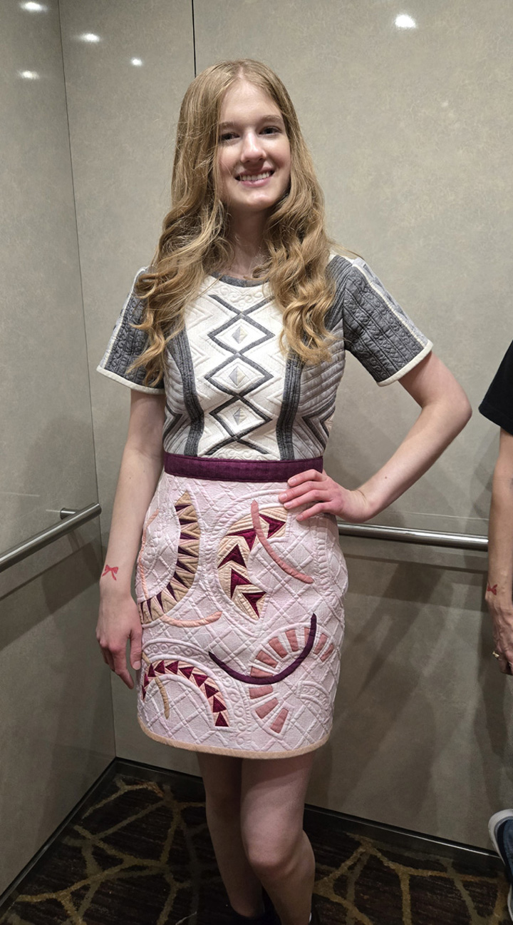 Woman wearing a patterned dress with geometric designs and a detailed skirt.