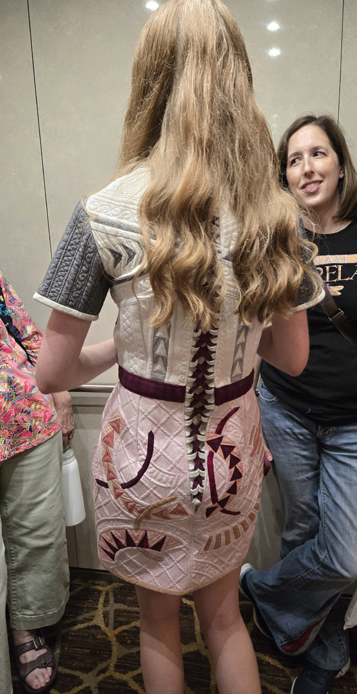 Woman in a unique dress with intricate red and black patterns on the back.