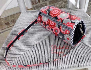 A small handbag with white, gray, and red-colored patterns