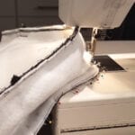 An ongoing sewing of a white bag