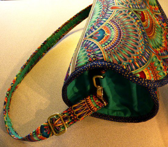 A small sling bag with green base and colorful designs