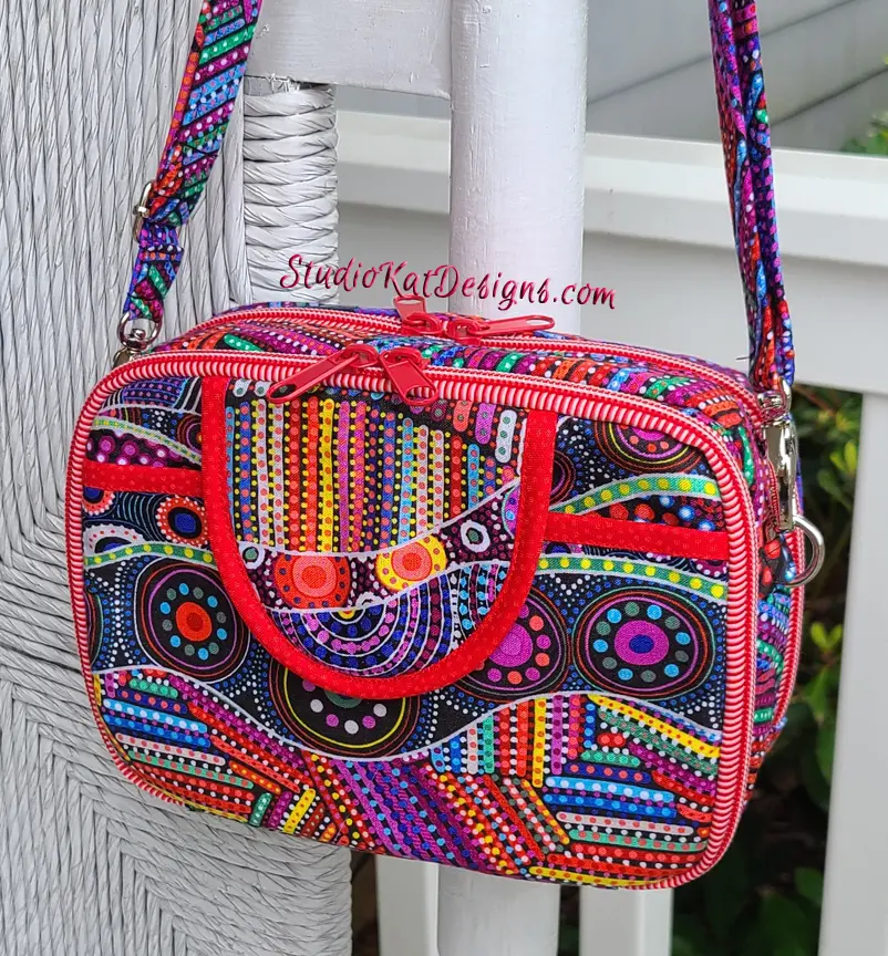A colorful sling bag with red zippers