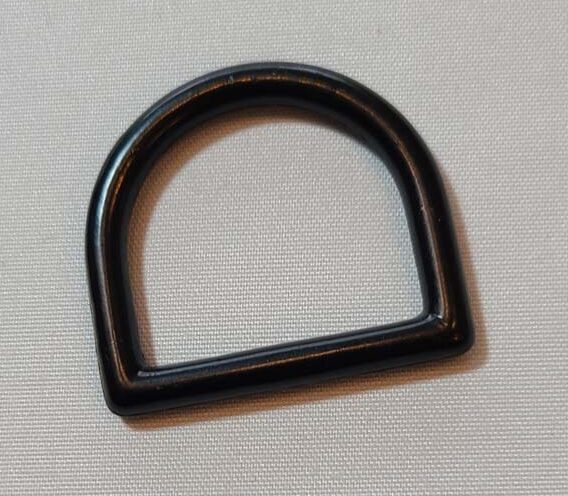 A black plastic d ring on a white surface.