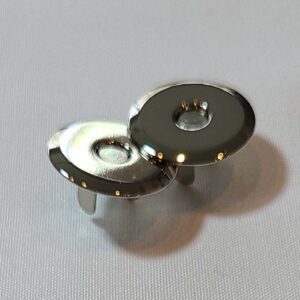 A pair of silver metal buttons on a white surface.