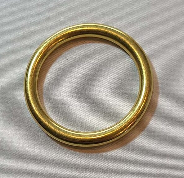 A brass ring on a white surface.