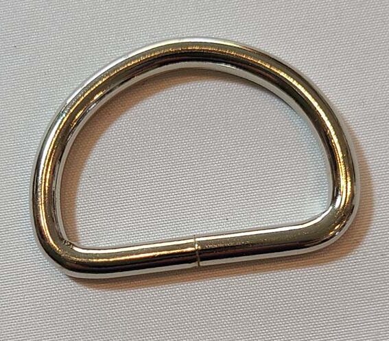 A stainless steel d-ring on a white surface.