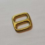A gold metal buckle on a white surface.
