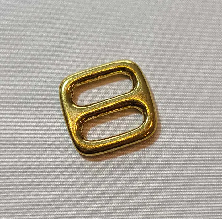 A gold metal buckle on a white surface.