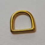 A gold plated d ring on a white surface.