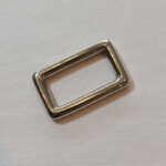 A square metal buckle on a white surface.