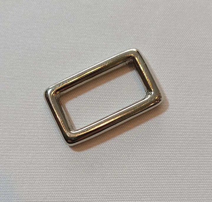 A square metal buckle on a white surface.