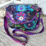 A purse with a colorful floral pattern sitting on a chair.