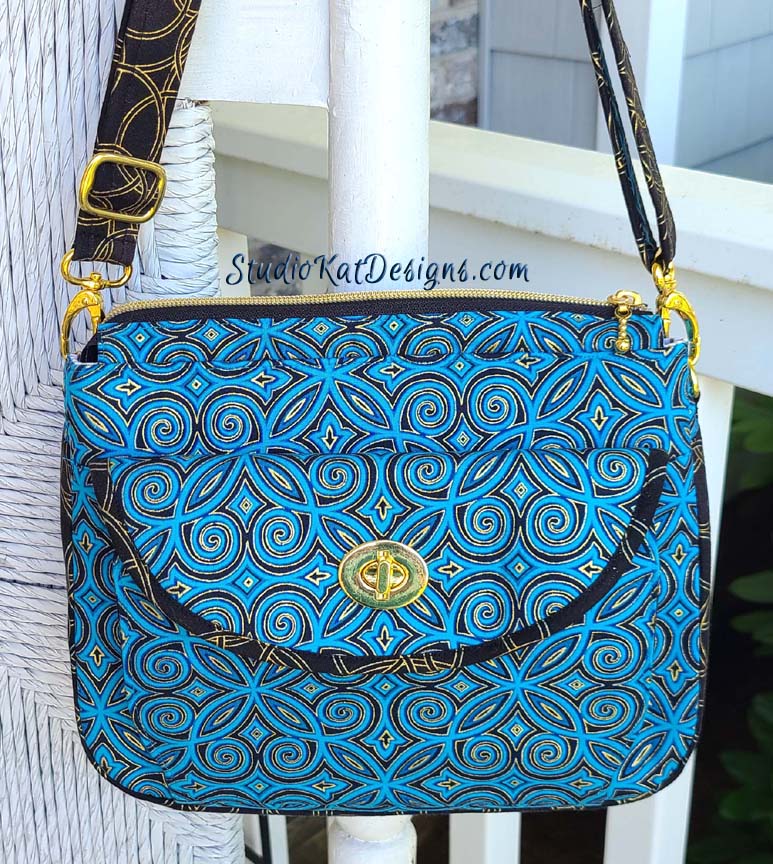 A blue and brown purse hanging on a porch.