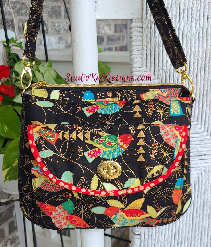 A black and gold purse with birds on it.