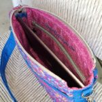 A blue and pink purse with a laptop inside.