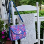 A blue and pink purse hanging on a white rocking chair.