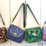 Four colorful handbags hanging on a hook.