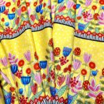 A yellow fabric with flowers and polka dots called Happy-go-Lucky.