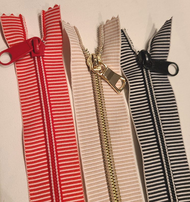 Three striped zippers on a white surface.