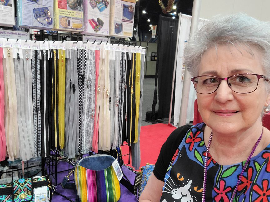 An older woman standing in front of a display of fabric.