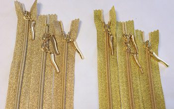 A set of gold zippers on a white surface.