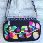 A black cross body bag with colorful leaves on it.