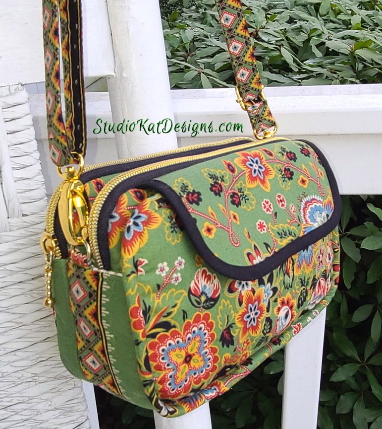 A green floral purse hanging on a white chair.