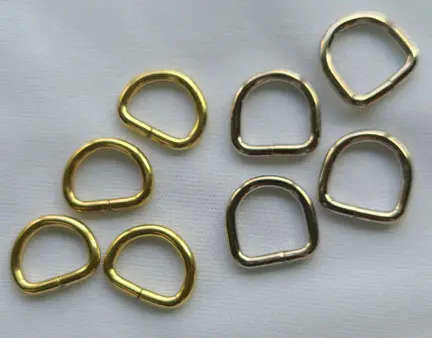 A set of brass d-rings on a white surface.