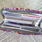 A colorful zippered wallet with pens and pencils inside.