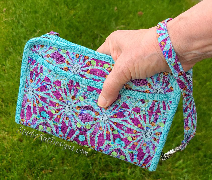 A person holding a purse with a blue and purple pattern.
