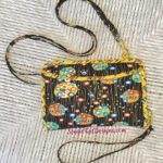 A black purse with colorful flowers on it.