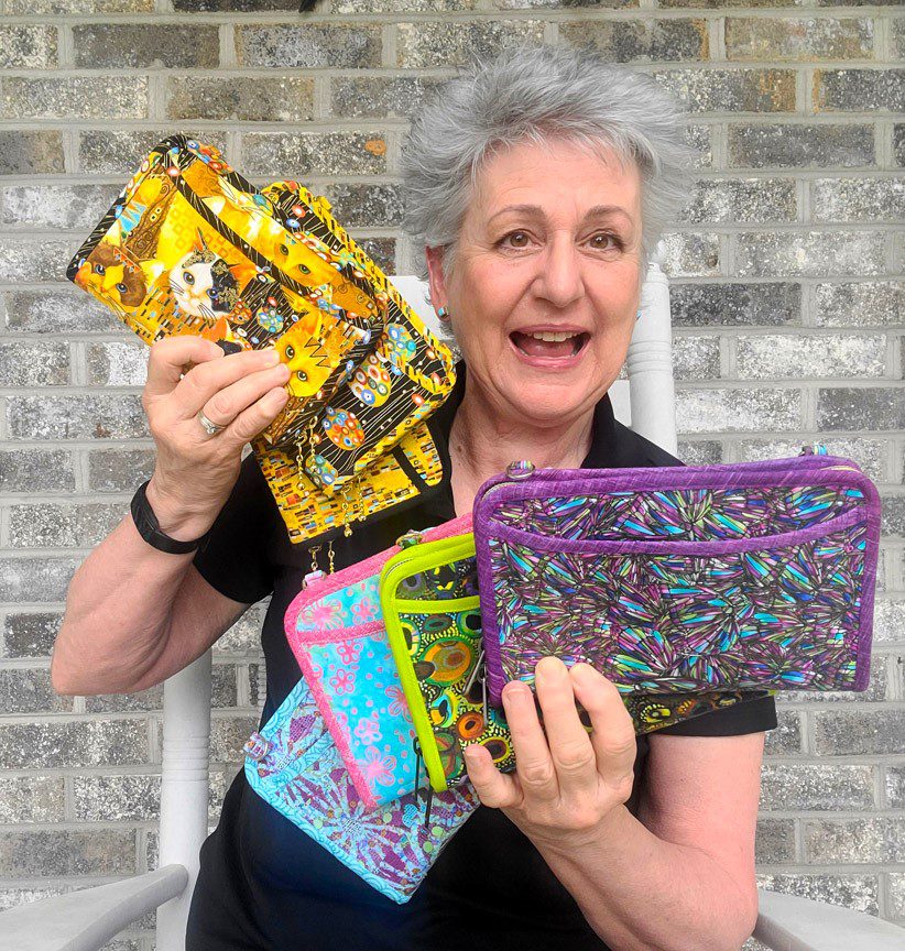 A woman holding a bunch of colorful purses.