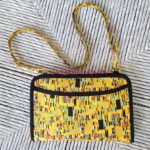 A yellow and black purse with a strap.
