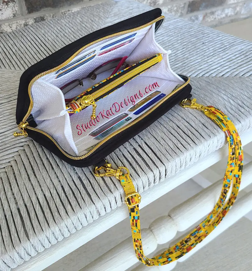 A purse with pens and pencils sitting on a table.