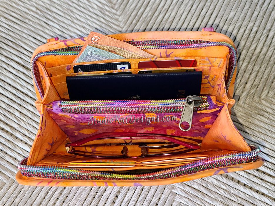 A purse with a wallet, cell phone, and other items in it.