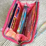 A pink purse with pens and pencils inside.