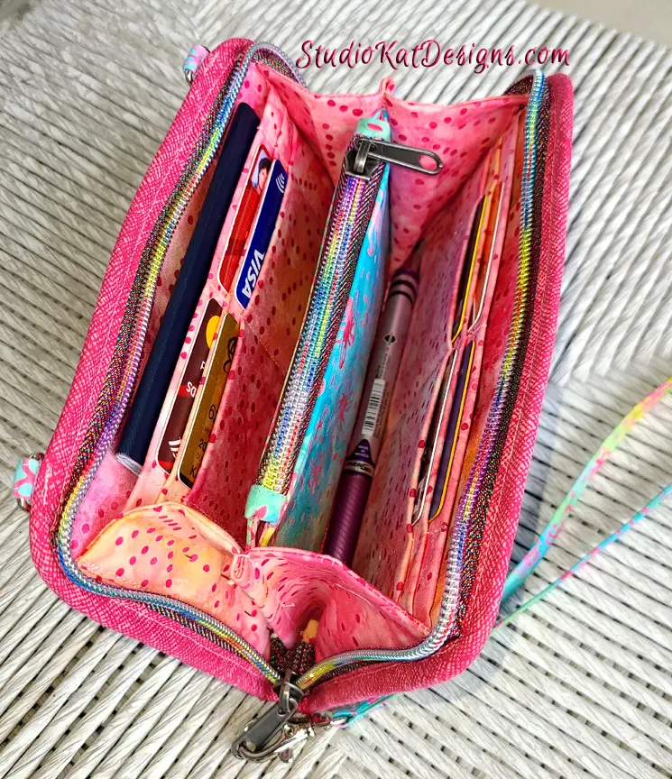 A pink purse with pens and pencils inside.