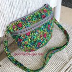 A colorful floral fanny pack sitting on a chair.