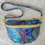 A blue and purple paisley fanny pack on a white surface.